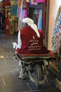 a porter in the souq, finding alternative use for his wheel barrow