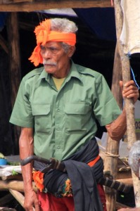another man, traditionally dressed with headband, sarong and machete